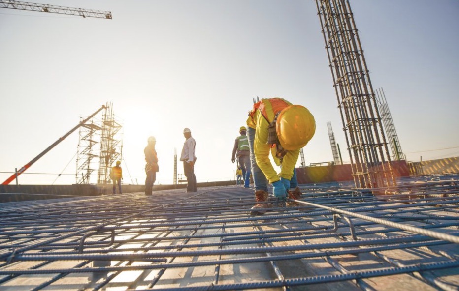 Construction crew securing reinforcement steel on a large-scale build at sunrise